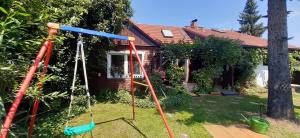 a swing set in the yard of a house at Spreewaldferienwohnungen Stein - Ferienhaus Bela Górka in Byhleguhre-Byhlen