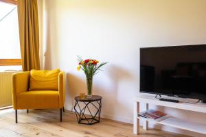 una sala de estar con una silla amarilla y un jarrón de flores en Ferienwohnung Bodensee Gaienhofen, en Gaienhofen