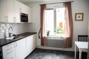 a kitchen with white cabinets and a sink and a window at Eksjö Stadshotell Annex in Eksjö
