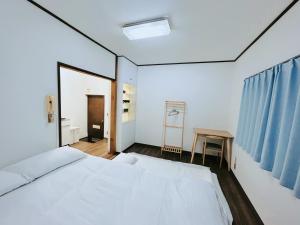 a bedroom with a large white bed and a table at Kokoro no sato・Ren in Kyoto