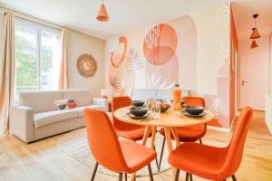 a living room with a table and orange chairs at Appartement équipé à 5 minutes de Paris in Ivry-sur-Seine