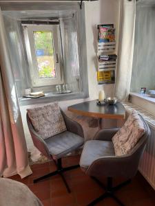 ein Wohnzimmer mit einem Tisch, 2 Stühlen, einem Tisch und einem Fenster in der Unterkunft Burgweg Ferienwohnung in Veringenstadt