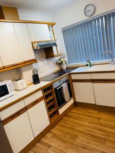 een keuken met witte kasten en een klok aan de muur bij Peaceful 3 Bed Home in Basildon