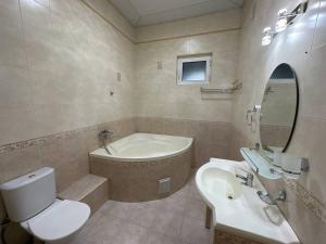 uma casa de banho com uma banheira, um WC e um lavatório. em VILLA ANOR em Yakkasaray