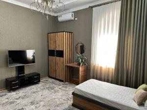 um quarto com uma cama e uma televisão de ecrã plano em VILLA ANOR em Yakkasaray