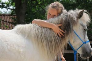 a girl is hugging a white pony with long hair at Ferienwohnung mit Sauna Reiterhof barrierefrei in Lichtenau