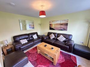 a living room with a leather couch and a coffee table at Greenwich Cottage - Part of the The Bay Filey Holiday Village with pool, gym and direct beach access, pub, restaurant, tennis and meadows walks in Reighton