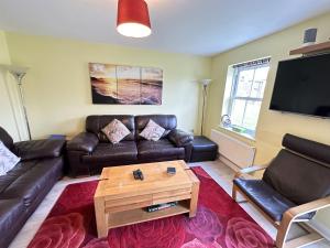 a living room with leather furniture and a flat screen tv at Greenwich Cottage - Part of the The Bay Filey Holiday Village with pool, gym and direct beach access, pub, restaurant, tennis and meadows walks in Reighton
