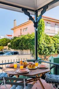 Estoril Historical Villa by the Sea في استوريل: طاولة مع طعام وكؤوس من عصير البرتقال على شرفة