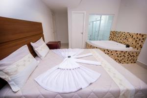 1 dormitorio con 1 cama blanca grande y bañera en Hotel Portal Guanambi, en Guanambi