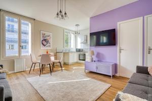 ein Wohnzimmer mit lilafarbenen Wänden sowie einem Tisch und Stühlen in der Unterkunft Appartement Parisien Porte d'Ivry in Ivry-sur-Seine