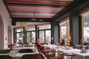 Alpine Spa Hotel Haus Hirt في باد جاستاين: غرفة طعام مع طاولات وأشخاص يجلسون على الطاولات