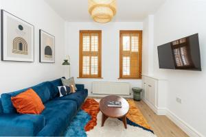 a living room with a blue couch and a table at Spacious 4BR 3-Storey Townhouse in Lively Deptford in London
