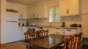 オータキャンツにあるSalmakis Villasの白いキャビネット、テーブルと椅子付きのキッチンが備わります。