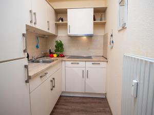uma pequena cozinha com armários brancos e um lavatório em Apartment Niki by Interhome em Norddeich
