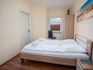um quarto com uma grande cama branca e uma cadeira em Apartment Niki by Interhome em Norddeich
