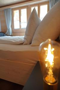 un letto con cuscini bianchi e una candela su un tavolo di Apartment Giferblick by Interhome a Gstaad