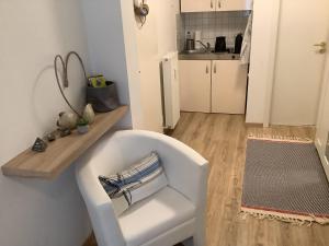 a white chair in a room with a kitchen at Gemütliche Koje in Rostock