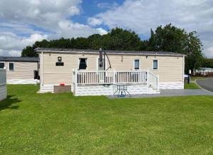 a mobile home with a porch and a deck at KMH Caravans at Flamingo Land in Kirby Misperton