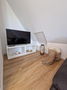 a living room with a flat screen tv and a wooden floor at Voll ausgestattetes 2 Zimmer Apartment Sanssouci in Osnabrück