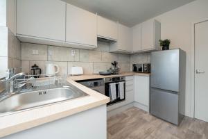 cocina con armarios blancos y nevera de acero inoxidable en Watling Apartments Tamworth, en Tamworth