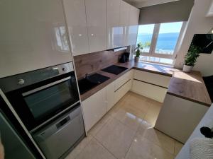 una cucina con mobili bianchi e una grande finestra di NIKO LUX Apartment with Jacuzzi only 70m from the beach a Dramalj