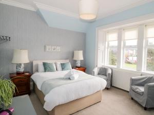 Un dormitorio con una gran cama blanca y una ventana en The Old Rectory, en Largs