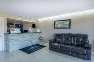 a living room with a leather couch and a bar at Howard Johnson by Wyndham Vero Beach/I-95 in Vero Beach