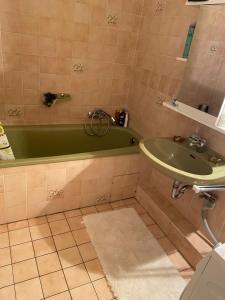 baño con bañera verde y lavamanos en 3 Zimmerwohnung für 4 Personen, en Bremen