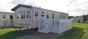 a large white house with a porch and stairs at KMH Caravans at Flamingo Land in Kirby Misperton