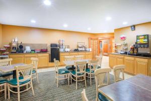 a restaurant with tables and chairs and a kitchen at Ramada by Wyndham Spirit Lake/Okoboji in Spirit Lake