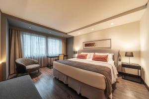 a hotel room with a large bed and a chair at Laghetto Stilo São Paulo in Sao Paulo