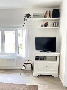 ein Wohnzimmer mit einem TV auf einem weißen Stand in der Unterkunft Le Rocher Trouville in Trouville-sur-Mer