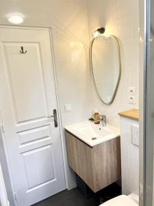 ein weißes Badezimmer mit einem Waschbecken und einem Spiegel in der Unterkunft Le Rocher Trouville in Trouville-sur-Mer