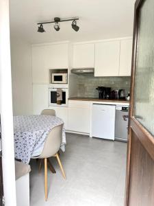 eine Küche mit einem Tisch und eine Küche mit weißen Schränken in der Unterkunft Le Rocher Trouville in Trouville-sur-Mer