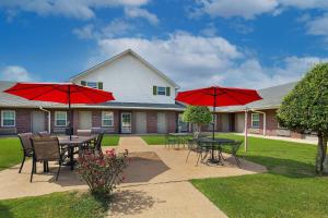 a patio with tables and chairs with red umbrellas at Days Inn by Wyndham Savannah in Savannah