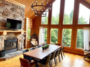 a dining room with a table and a fireplace at Chalet Authentik 50 - Hot tub, Pools, Lake & Resort in Mille-Isles