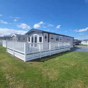 a mobile home with a white fence in the grass at KMH Caravans at Flamingo Land in Kirby Misperton