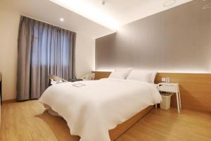 a bedroom with a large white bed and a window at Urban Stay in Cheonan