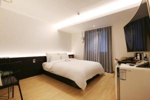 a bedroom with a white bed and a television at Urban Stay in Cheonan