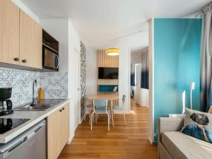 巴黎的住宿－巴黎拉維萊特阿德吉奧阿克瑟斯公寓酒店，厨房以及带桌子和沙发的客厅。