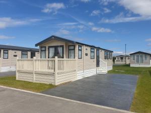 a modular house with a porch in a parking lot at KMH Caravans at Flamingo Land in Kirby Misperton