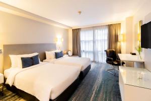 una camera d'albergo con 2 letti e una scrivania di Best Western Sukhumvit 20 a Bangkok