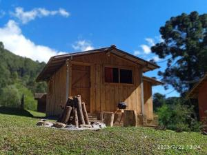 uma pequena casa de madeira com uma pilha de troncos em Rancho Toa-toa próximo a Gonçalves MG em Sapucaí-Mirim