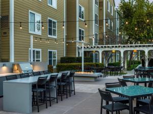 un patio avec des tables et des chaises en face d'un bâtiment dans l'établissement Homewood Suites by Hilton Newark Fremont, à Fremont