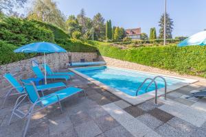 a swimming pool with blue chairs and umbrellas at Le Petit Lac in Bourganeuf