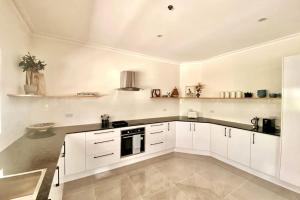 una cocina blanca con armarios blancos y fregadero en Luxury and cosy family retreat, 