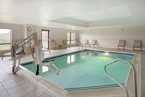 a pool in a hotel room with chairs and tables at Comfort Suites in Bloomsburg