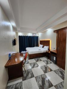 una camera d'albergo con letto e scrivania di Pulickal Heights Hotel a Entebbe