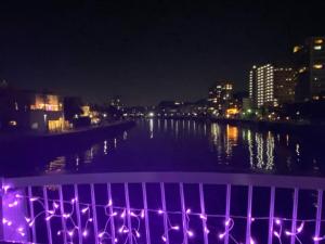 uma vista para um rio à noite com luzes roxas em Enoshima Beach - Vacation STAY 07420v em Fujisawa